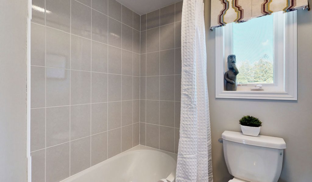 Picture Homes Model Home - Bathtub With Curtain and Toilet in Front of Window in Upstairs Washroom